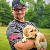 K9JF trainer holding yellow lab puppy